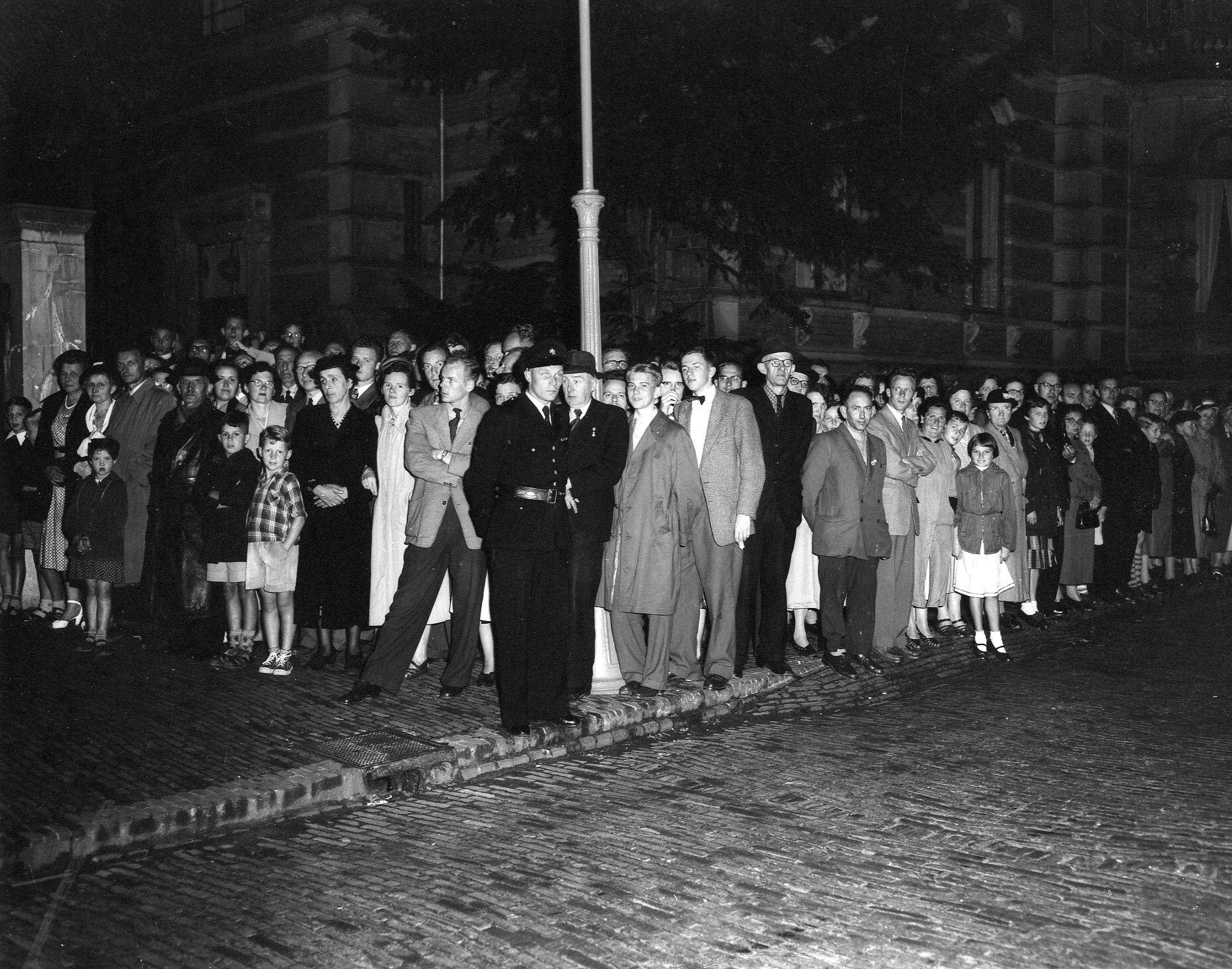 Afbeelding van een groep mensen die staat te wachten op de aankomst van het stoffelijk overschot van Kardinaal de Jong bij het Aartsbisschoppelijk Paleis (Maliebaan 40) te Utrecht, 1955. Fotograaf F.F. van de Werff.