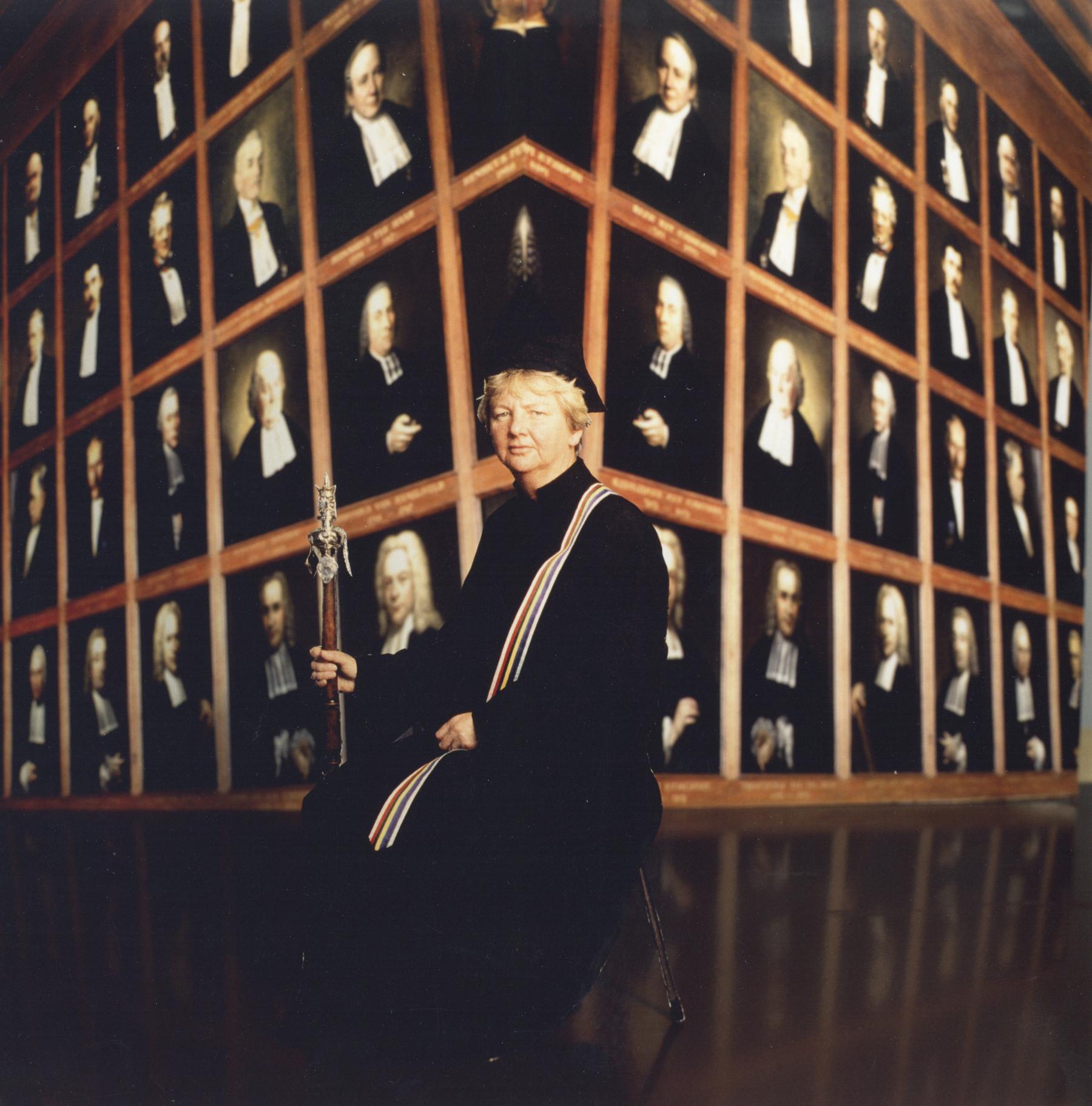 Portret van Greetje van den Berg-Bos, pedel van de Universiteit Utrecht, in de senaatszaal van het Academiegebouw (Domplein 29) te Utrecht.<br />
<br />
N.B. Greetje van den Berg-Bos was de eerste en lange tijd enige vrouwelijke pedel in Nederland. Fotograaf D. Scagliola.<br />
